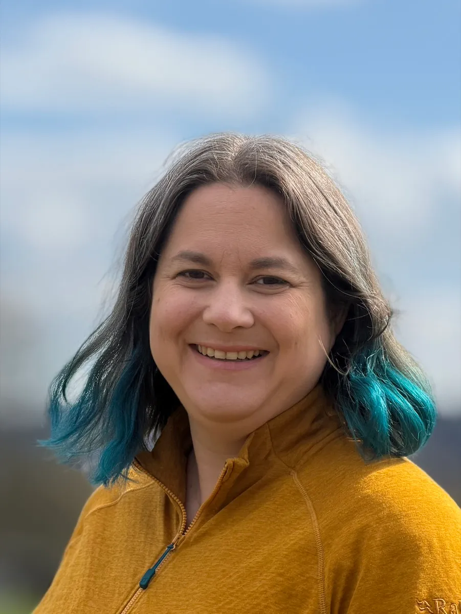 Sara Rüegg im Freien, lächelnd vor blauem Himmel