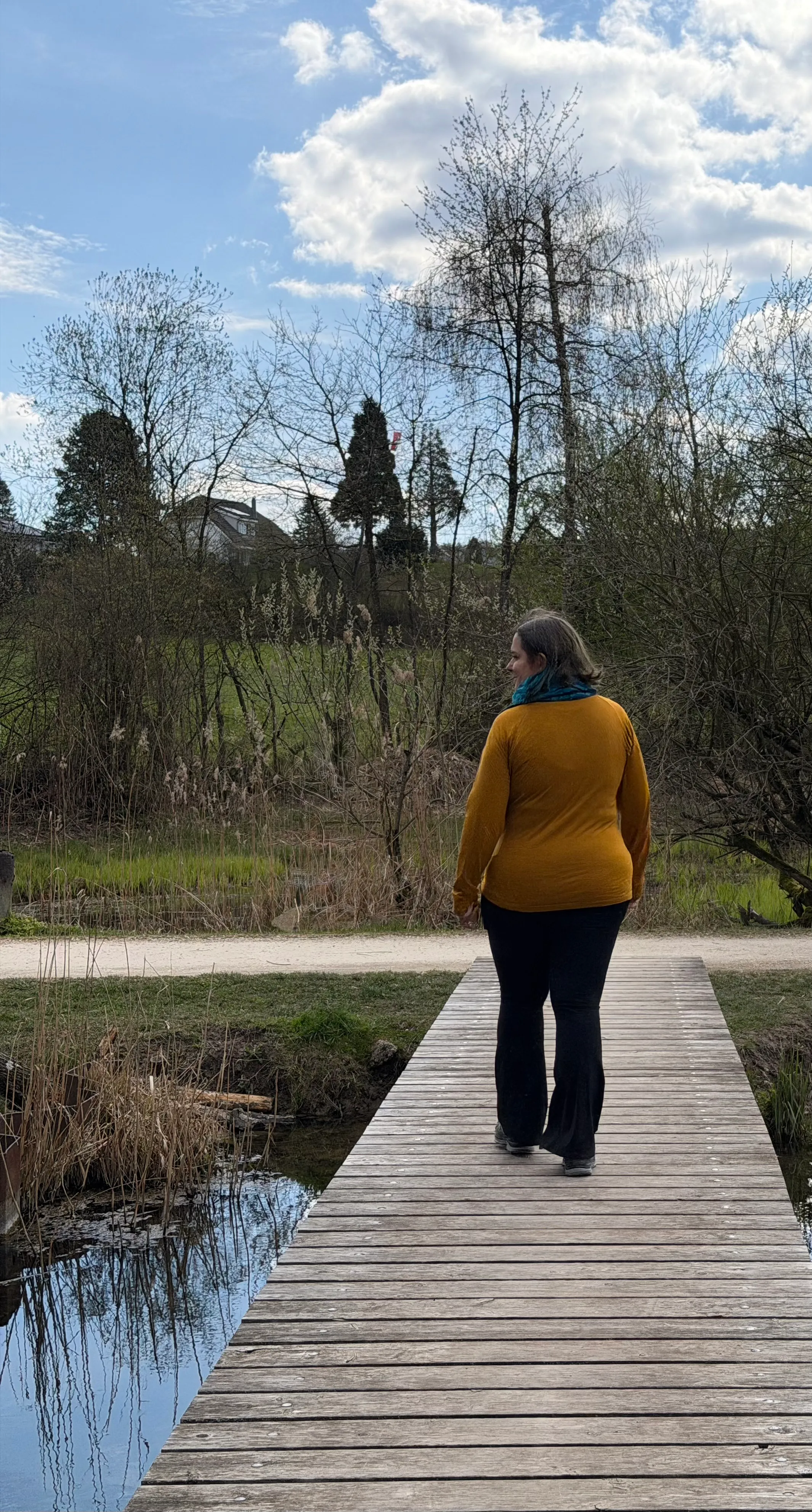 Sara Rüegg spaziert über einen Holzsteg am Wasser, umgeben von Natur